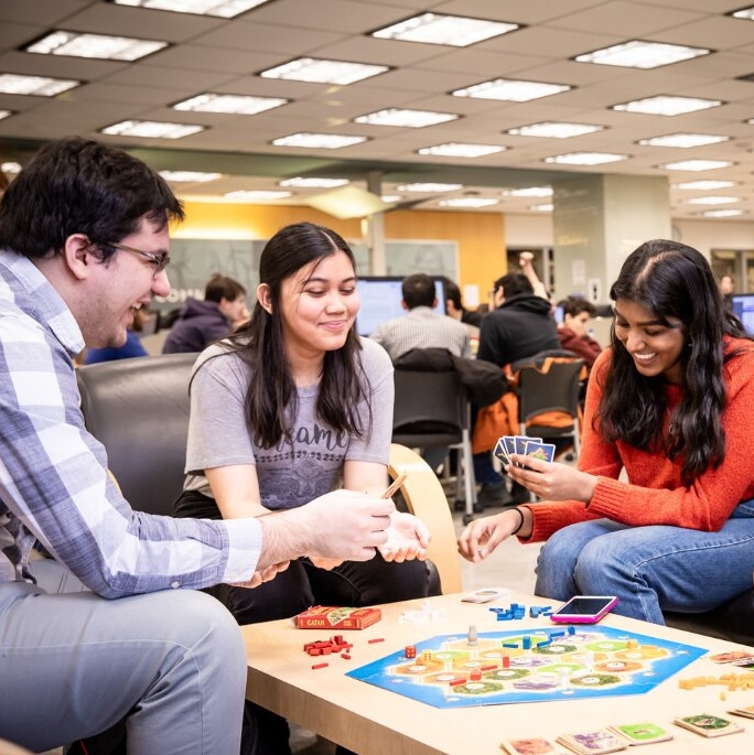 Students gathered around, socializing and playing board games.